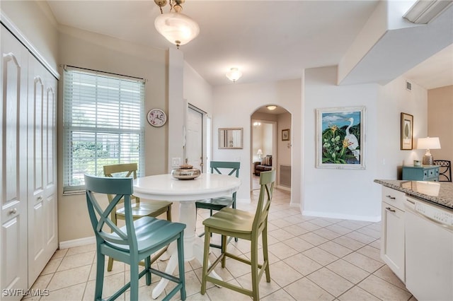 dining room featuring arched walkways, light tile patterned flooring, visible vents, and baseboards