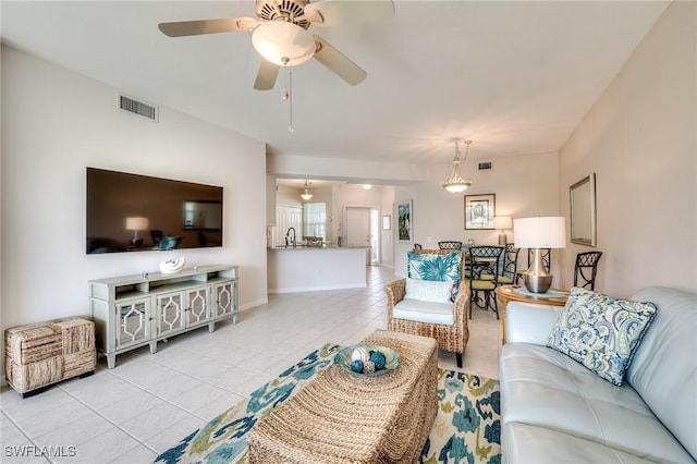 living room featuring light tile patterned floors, baseboards, visible vents, and a ceiling fan