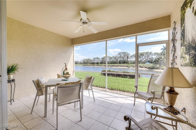 sunroom / solarium featuring ceiling fan and a water view