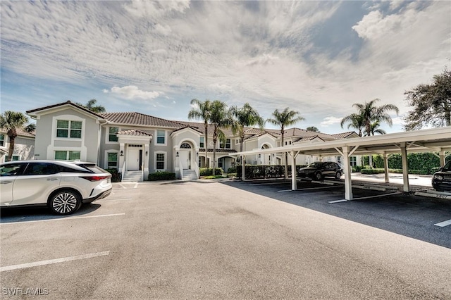 view of front of property with a tile roof, covered and uncovered parking, and stucco siding