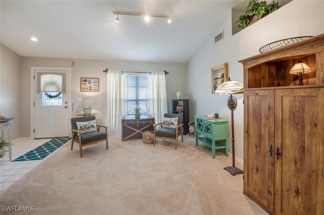 living area featuring rail lighting, lofted ceiling, and light colored carpet