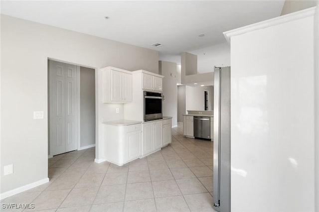 kitchen with light tile patterned floors, baseboards, stainless steel appliances, light countertops, and white cabinetry