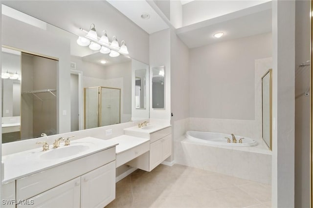 bathroom with a walk in closet, a garden tub, a shower stall, vanity, and tile patterned floors