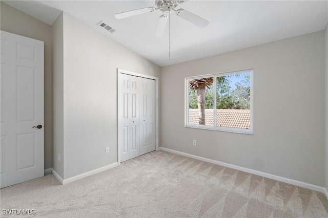 unfurnished bedroom featuring visible vents, vaulted ceiling, a closet, and light colored carpet