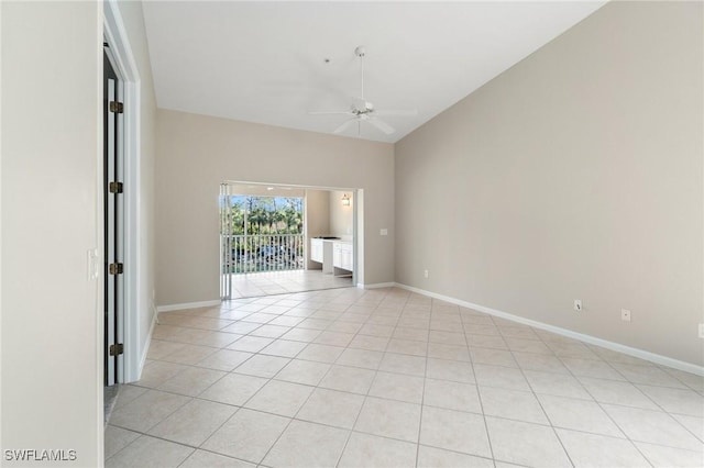 empty room with vaulted ceiling, light tile patterned floors, a ceiling fan, and baseboards