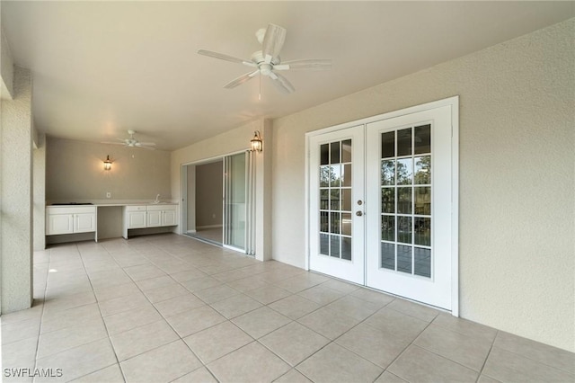 spare room featuring a sink, light tile patterned floors, a ceiling fan, and french doors