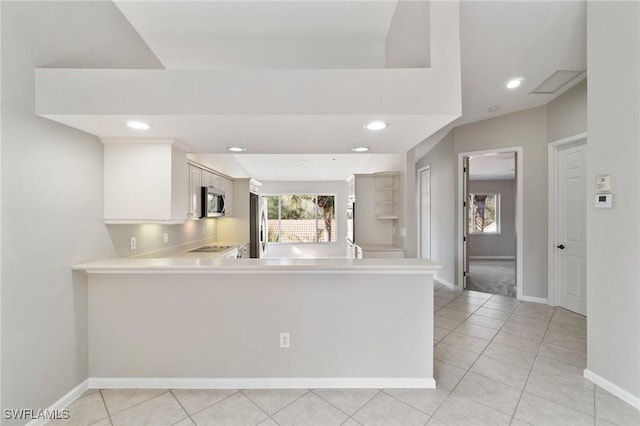 kitchen featuring a peninsula, white cabinets, light countertops, appliances with stainless steel finishes, and a wealth of natural light