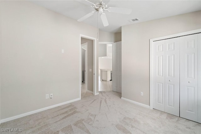 unfurnished bedroom with a closet, visible vents, light carpet, ceiling fan, and baseboards