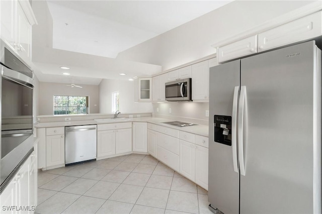 kitchen with appliances with stainless steel finishes, white cabinetry, a sink, and glass insert cabinets