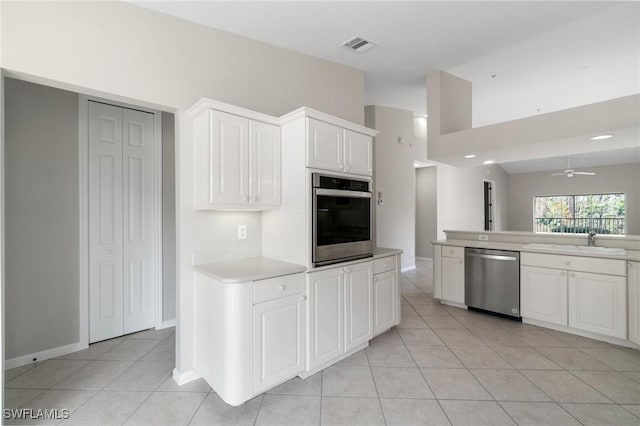 kitchen featuring light tile patterned floors, a sink, white cabinets, light countertops, and appliances with stainless steel finishes