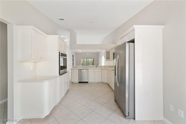 kitchen featuring light tile patterned flooring, stainless steel appliances, a peninsula, white cabinets, and light countertops