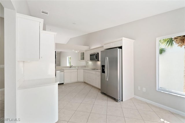 kitchen featuring appliances with stainless steel finishes, white cabinets, light countertops, and plenty of natural light