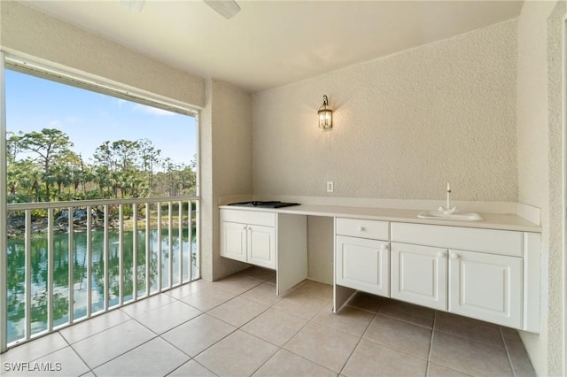 bathroom with a textured wall, a water view, a sink, and tile patterned floors