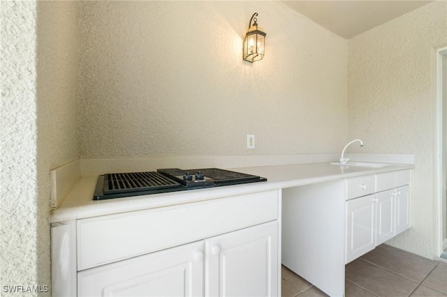 kitchen with light tile patterned floors, light countertops, a sink, and white cabinetry