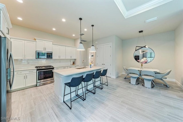 kitchen featuring white cabinetry, appliances with stainless steel finishes, and hanging light fixtures