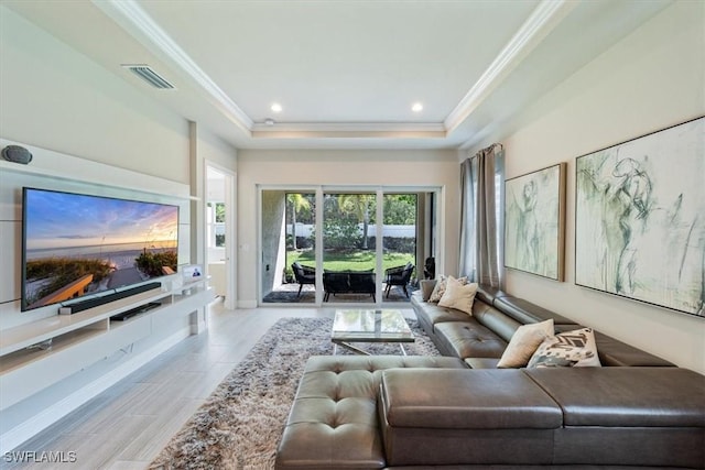 living room with ornamental molding, a raised ceiling, and light hardwood / wood-style floors