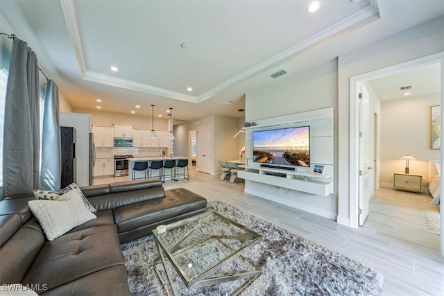 living room featuring a raised ceiling and ornamental molding