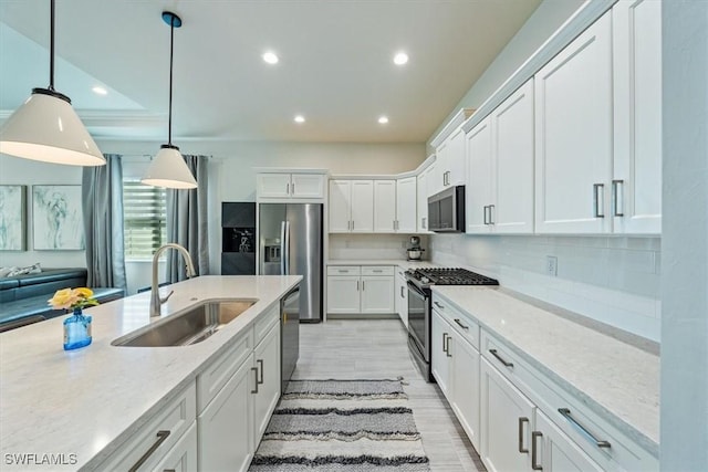 kitchen featuring sink, white cabinetry, light stone counters, pendant lighting, and stainless steel appliances