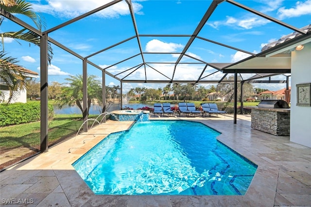 view of swimming pool featuring glass enclosure, a patio, a water view, a pool with connected hot tub, and exterior kitchen