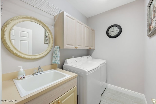 laundry room featuring a sink, baseboards, cabinet space, and separate washer and dryer