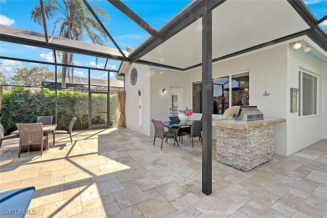 view of patio / terrace with a lanai, outdoor dining space, and an outdoor kitchen