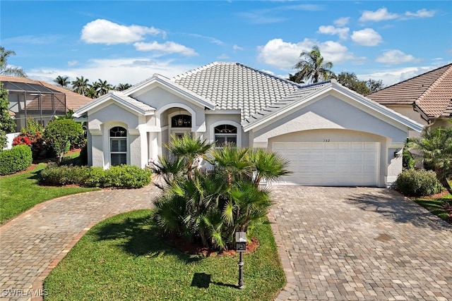 view of front of home with decorative driveway, a tiled roof, an attached garage, and stucco siding