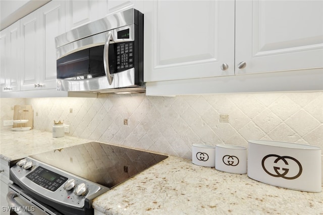 kitchen featuring stainless steel appliances, decorative backsplash, white cabinetry, and light stone countertops