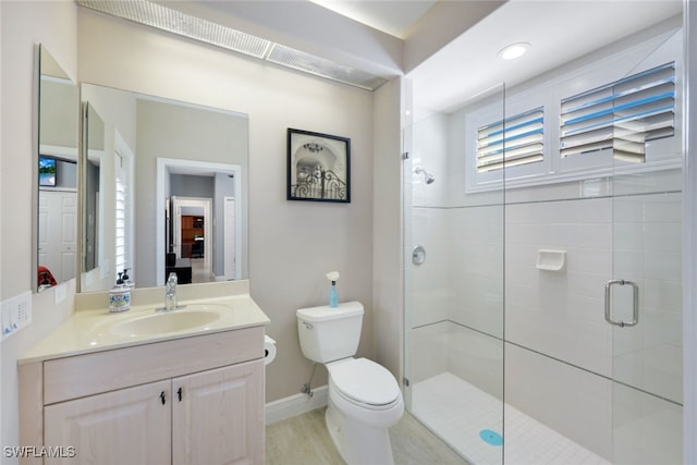 bathroom with toilet, a stall shower, baseboards, and vanity