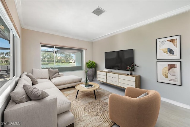 living area with visible vents, wood finished floors, baseboards, and ornamental molding