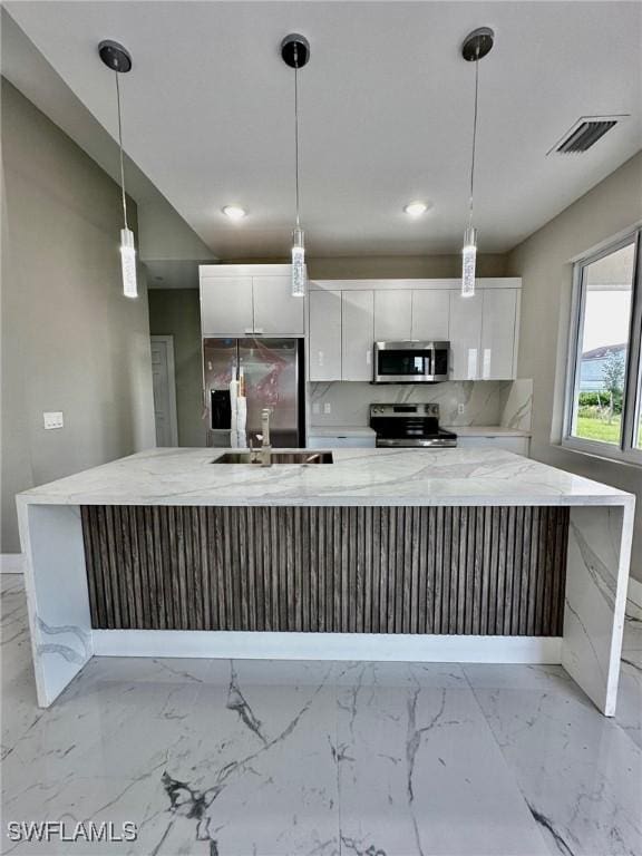 kitchen with a spacious island, appliances with stainless steel finishes, hanging light fixtures, and white cabinets