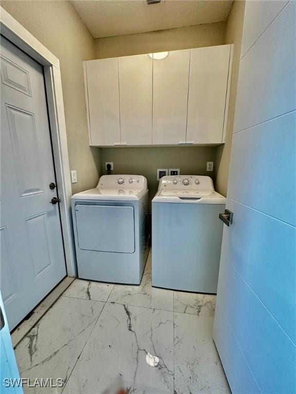 clothes washing area with independent washer and dryer and cabinets