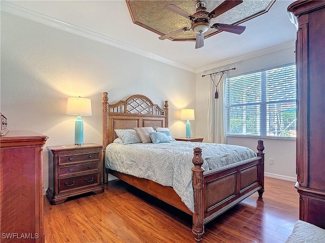 bedroom featuring a ceiling fan, baseboards, ornamental molding, and wood finished floors