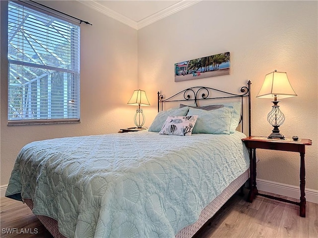 bedroom with crown molding, baseboards, and wood finished floors