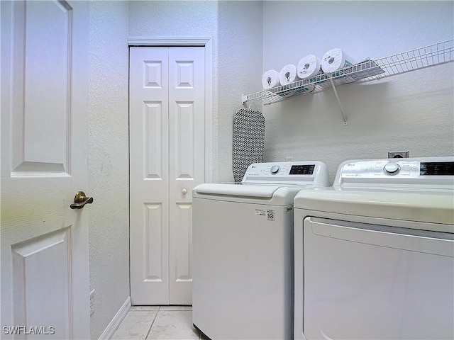 clothes washing area with laundry area, marble finish floor, washer and clothes dryer, and a textured wall