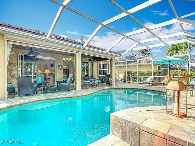 outdoor pool with a patio area, ceiling fan, and glass enclosure