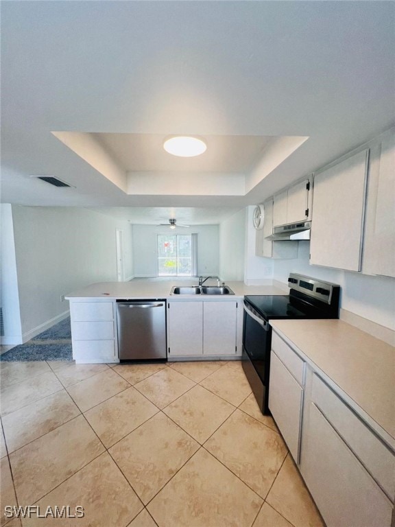 kitchen featuring a raised ceiling, appliances with stainless steel finishes, sink, and white cabinets