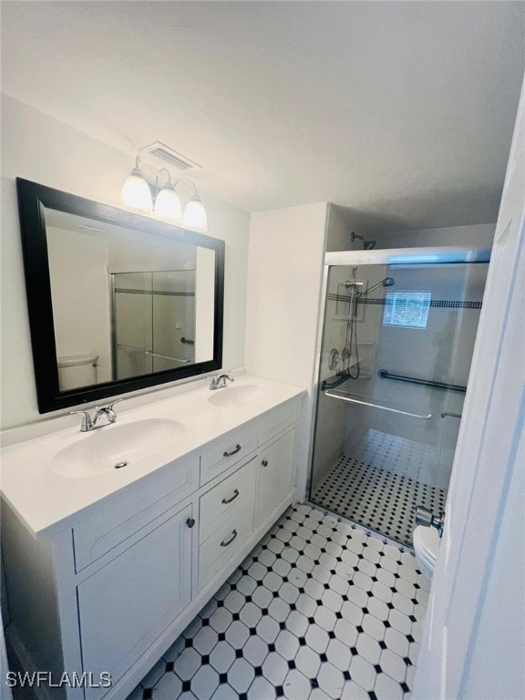 bathroom featuring vanity, a shower with shower door, and toilet