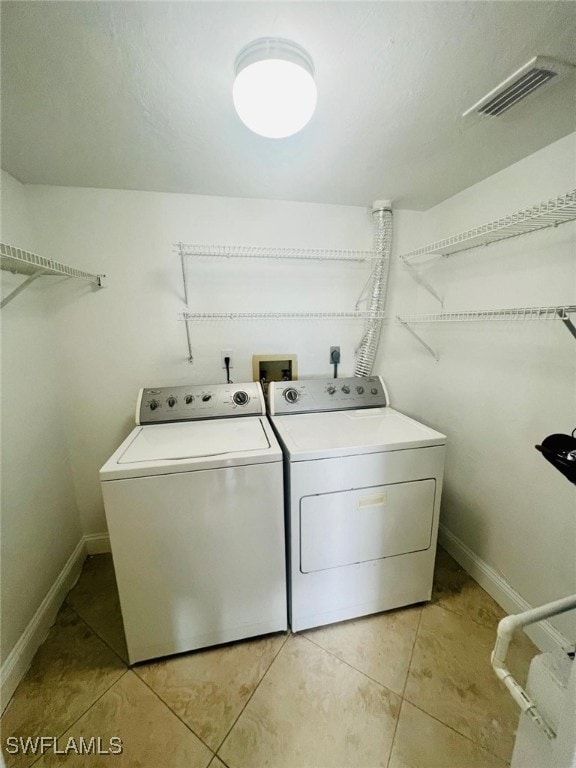 laundry room with washing machine and clothes dryer and light tile patterned flooring