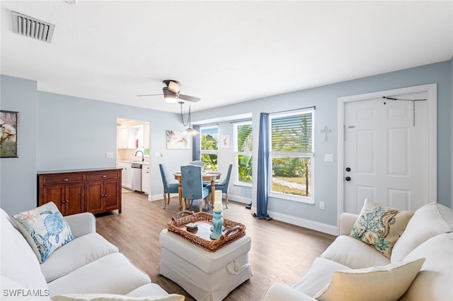 living room featuring sink, light hardwood / wood-style floors, and ceiling fan