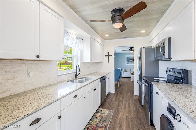 kitchen with stainless steel appliances, washer / dryer, sink, and white cabinets