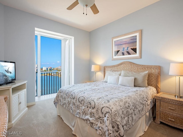 carpeted bedroom with access to exterior, ceiling fan, and a water view