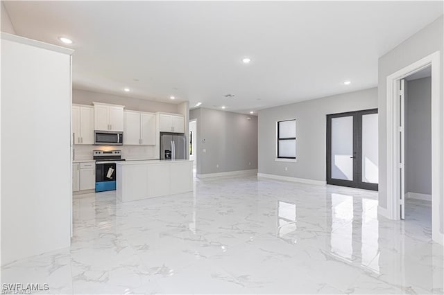 kitchen featuring tasteful backsplash, white cabinetry, a center island, stainless steel appliances, and french doors