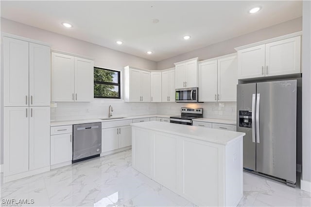 kitchen featuring stainless steel appliances, a kitchen island, sink, and white cabinets