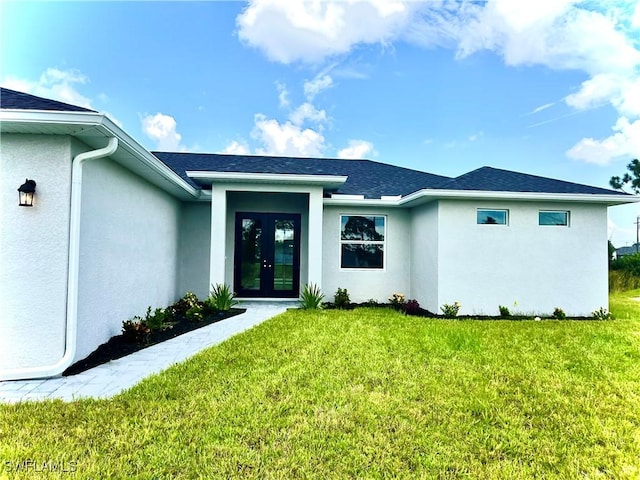 entrance to property featuring a yard, french doors, a shingled roof, and stucco siding