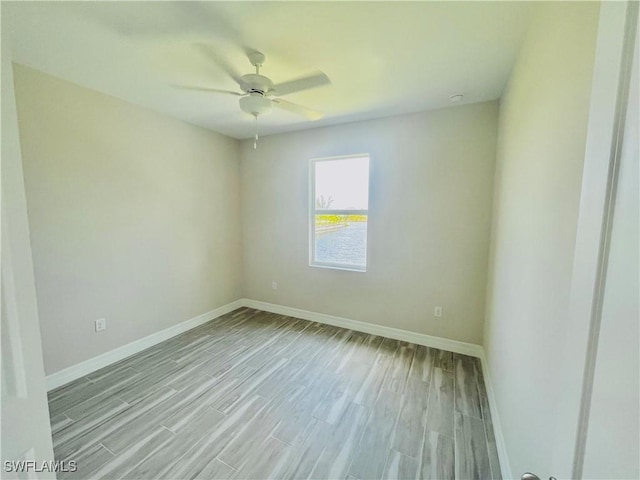 spare room featuring light wood-style floors, baseboards, and a ceiling fan