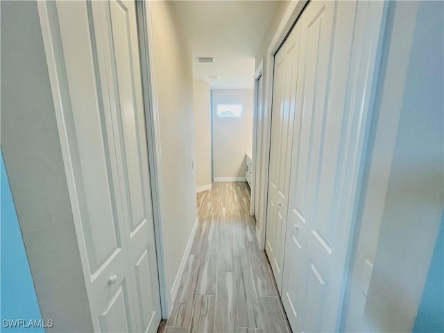 hallway featuring baseboards, visible vents, and wood tiled floor