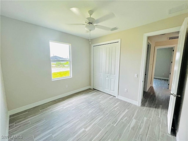 unfurnished bedroom featuring light wood finished floors, visible vents, baseboards, and a closet