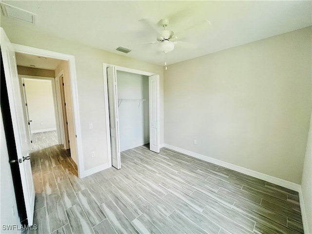 unfurnished bedroom with wood finish floors, a closet, visible vents, and baseboards