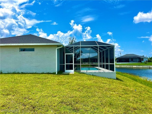 back of property featuring glass enclosure, a yard, a water view, and stucco siding