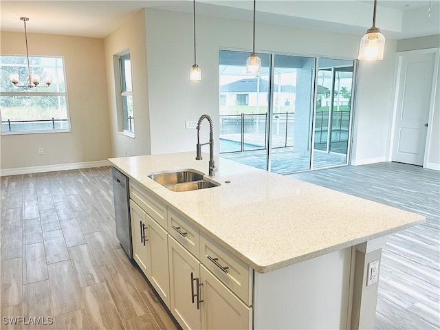 kitchen with light stone counters, a center island with sink, white cabinets, a sink, and dishwasher